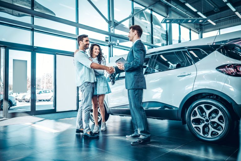 Young couple shaking hands with sales agent after a successful car buying.