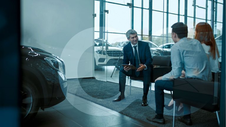 Man on tablet talking to a couple in dealership